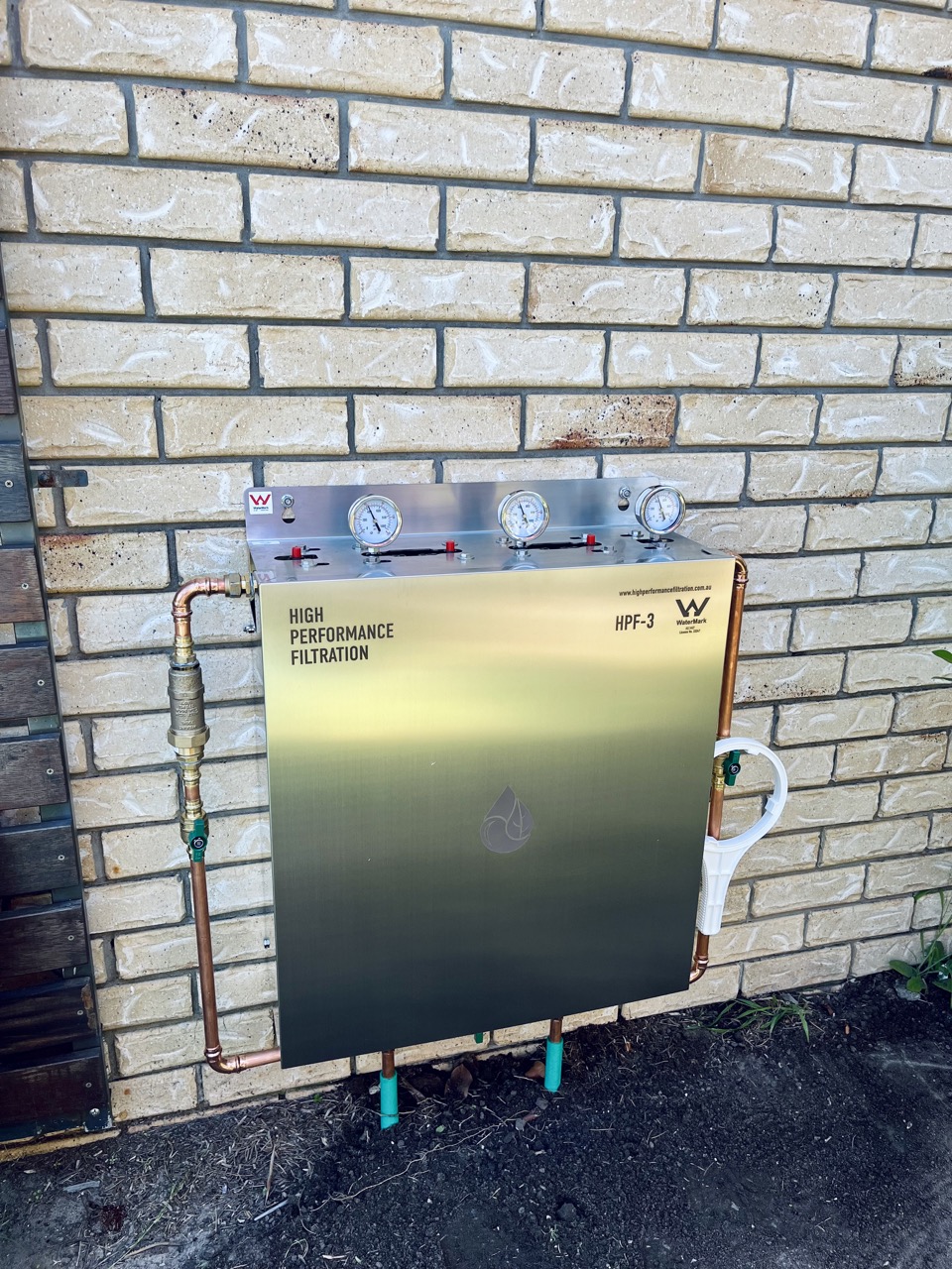 Whole-house water filter installed on a brick wall